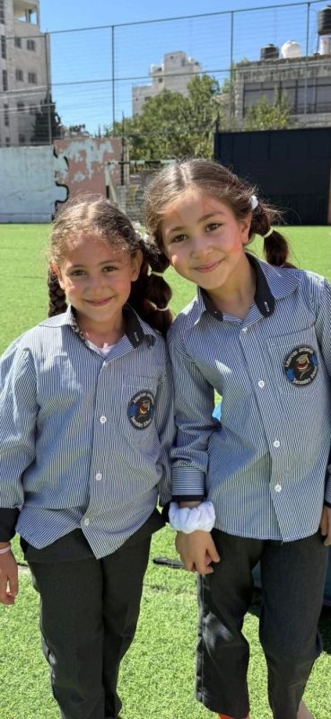 Two young students smile together on the school field
