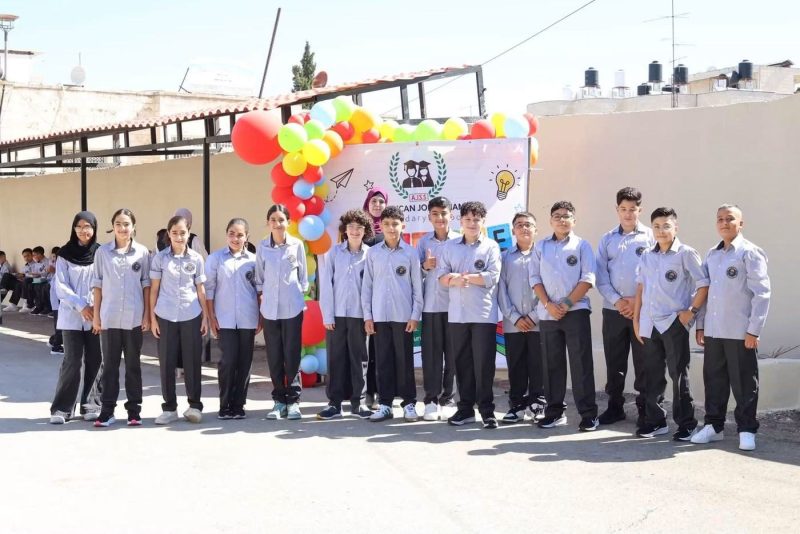 Students in school uniform line up in front of the AJSS welcome banner and balloons