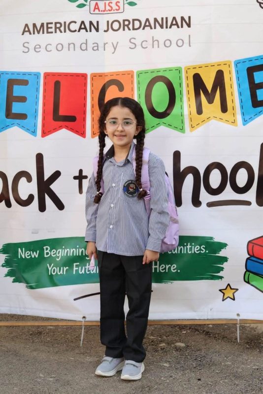 A student stands in front of the AJSS “Welcome back to school” banner