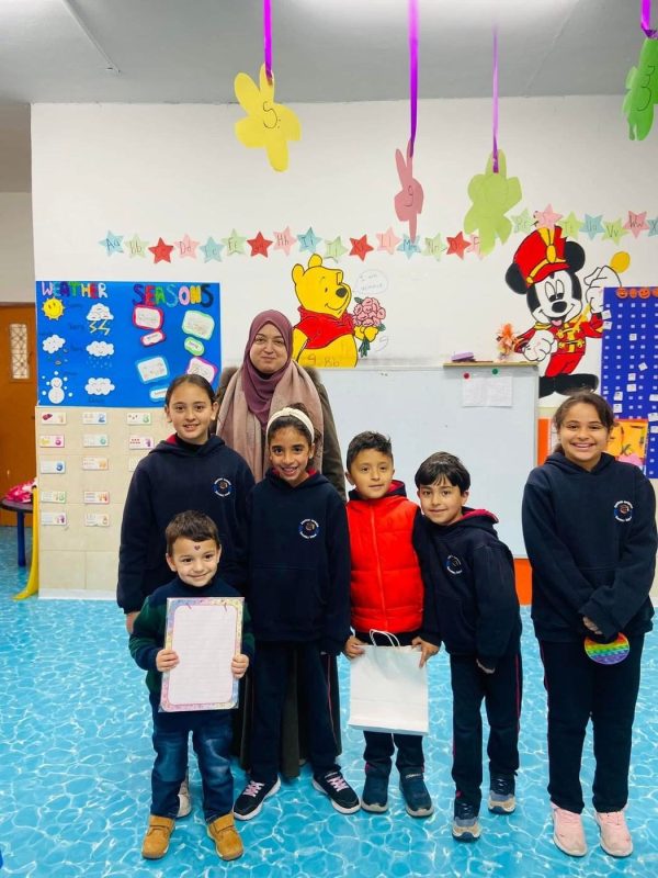 أطفال الروضة يحملون شهاداتهم مع معلمتهم في صف ملوّن