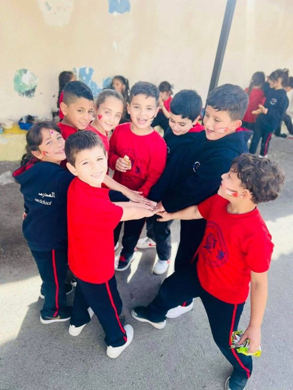 طلاب صغار بالزي الأحمر والكحلي يتجمّعون معًا خلال نشاط صفي