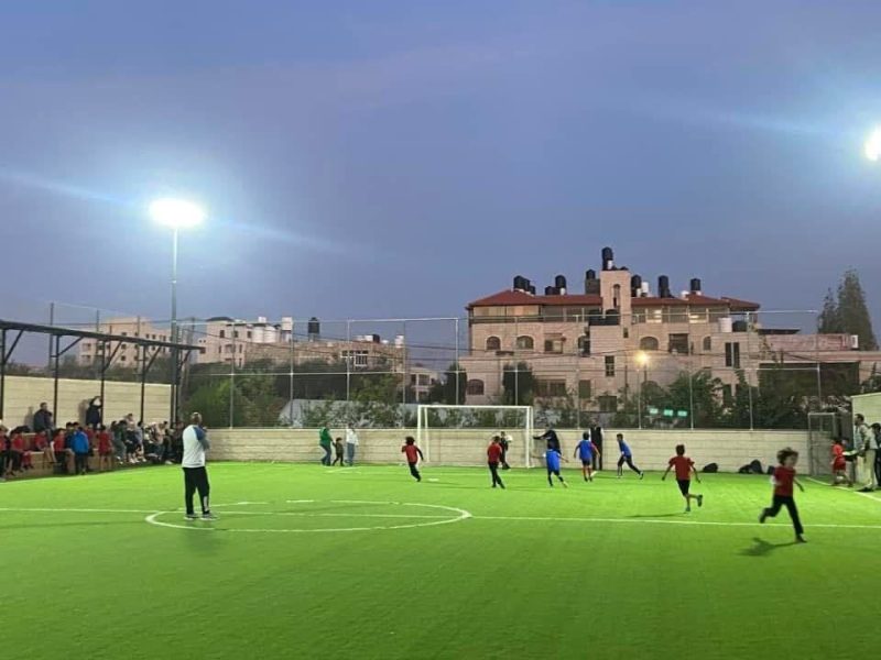 Students play football on the floodlit school pitch in the evening